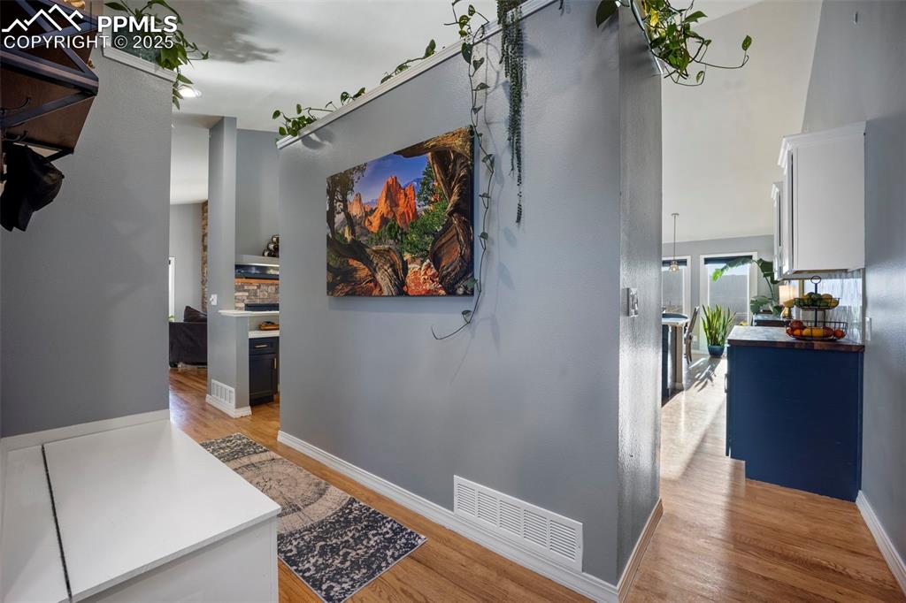 Hallway featuring visible vents, light wood finished floors, and baseboards