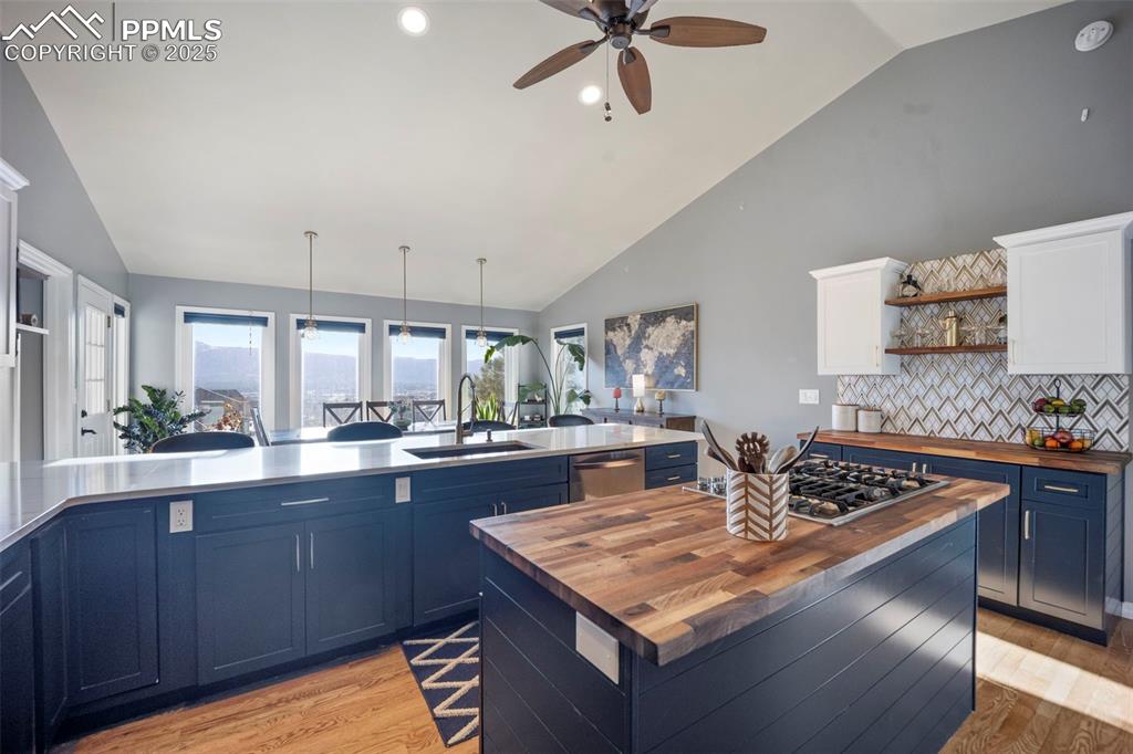 Kitchen with wood counters, appliances with stainless steel finishes, blue cabinets, and a sink