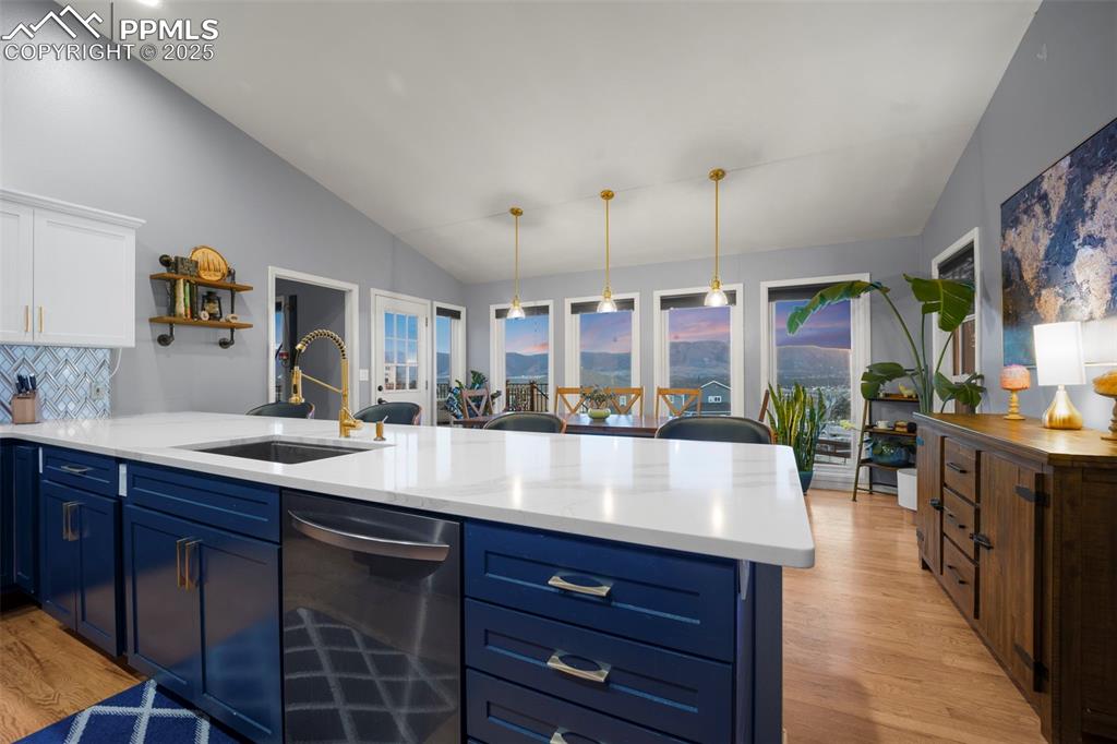 Kitchen with a sink, light wood-style floors, light countertops, blue cabinets, and dishwasher