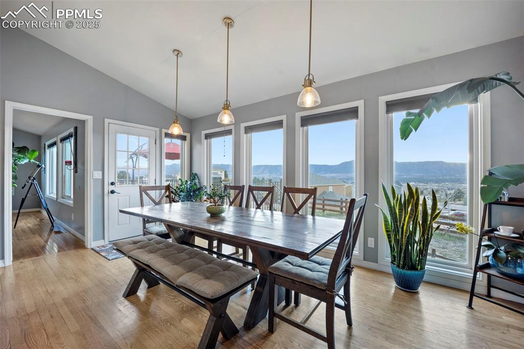 Dining room featuring a mountain view, baseboards, lofted ceiling, and light wood-style floors