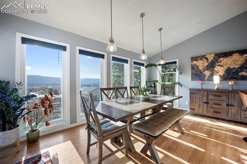 Dining space featuring wood finished floors, plenty of natural light, and vaulted ceiling