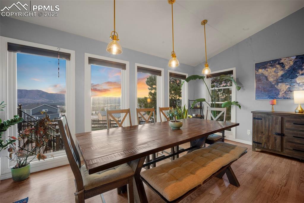Dining room featuring baseboards, a mountain view, light wood finished floors, and vaulted ceiling