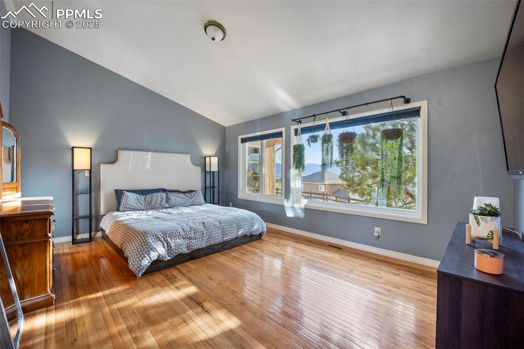 Bedroom featuring baseboards, vaulted ceiling, and wood-type flooring