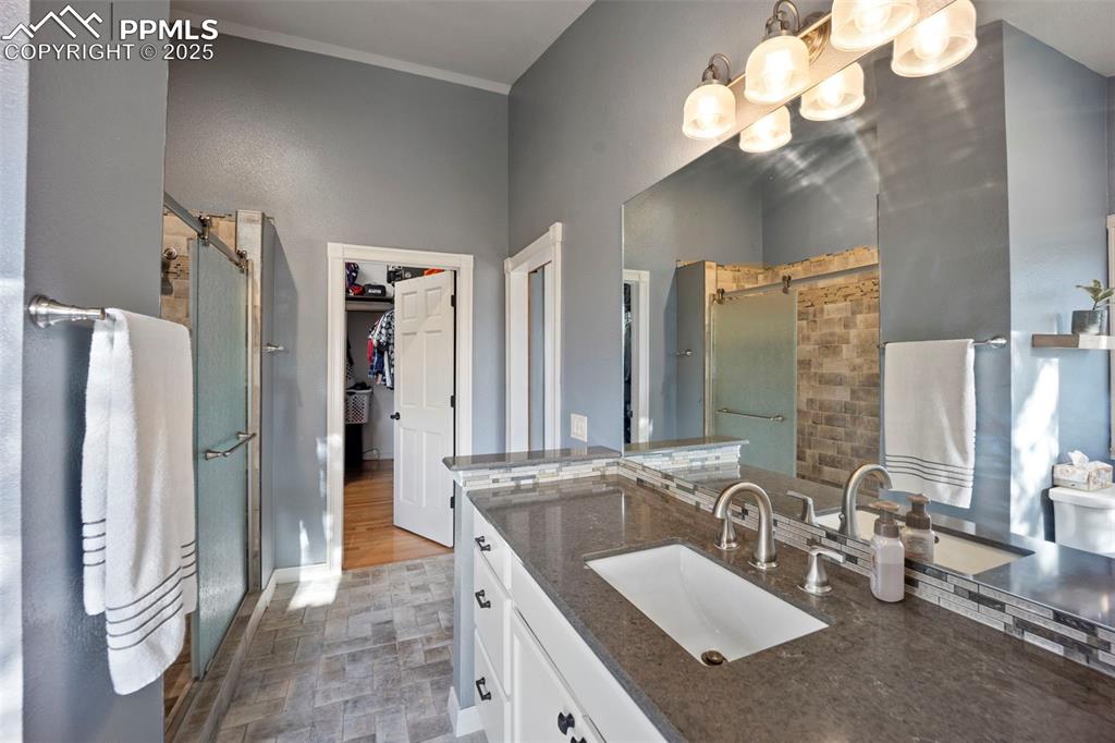 Full bath featuring a chandelier, a shower stall, ornamental molding, vanity, and a spacious closet