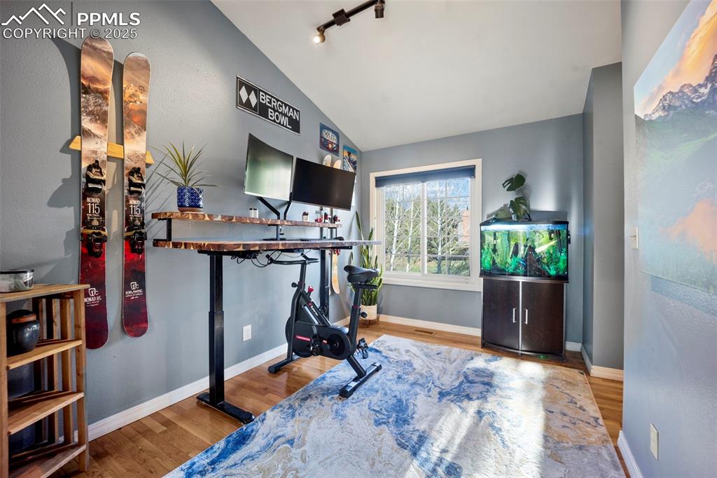 Exercise area featuring lofted ceiling, wood finished floors, and baseboards