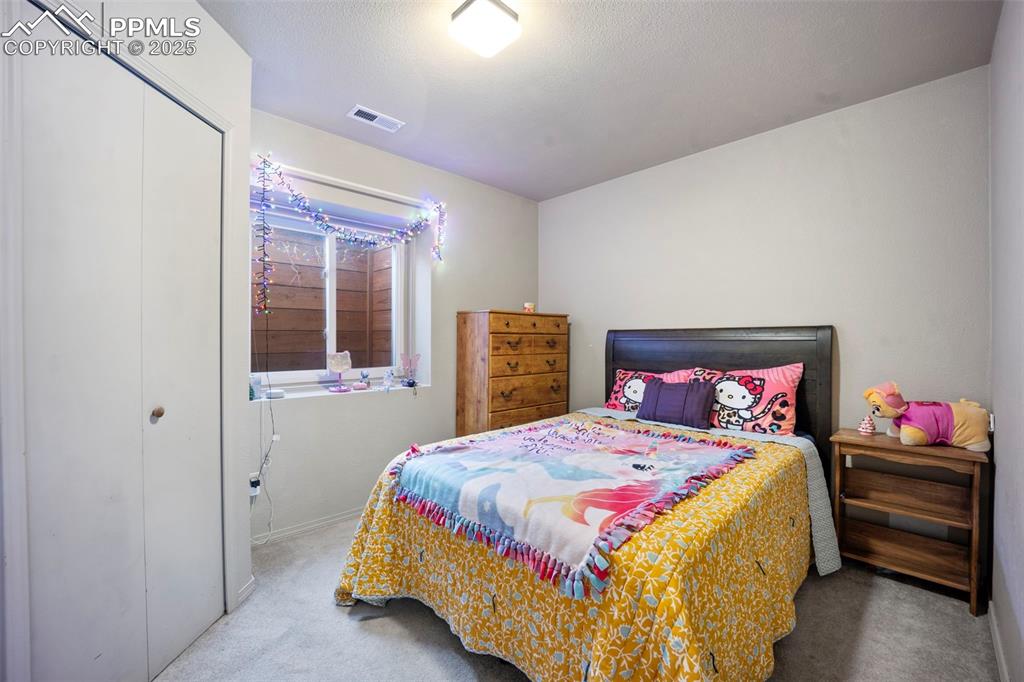 Bedroom with carpet, visible vents, baseboards, and a closet