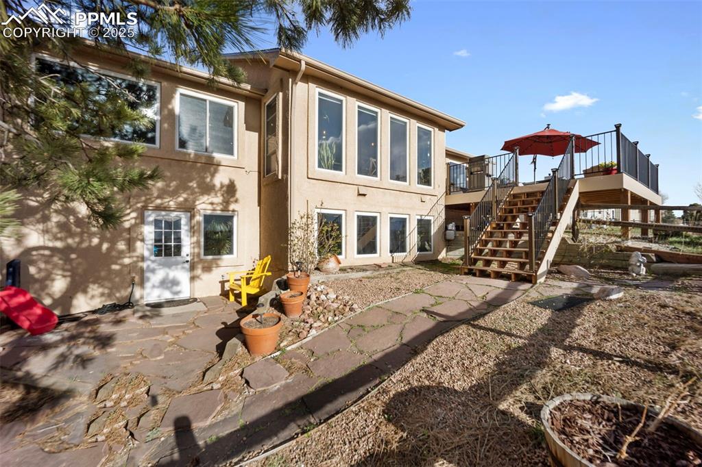 Back of house with stairs, stucco siding, and a wooden deck
