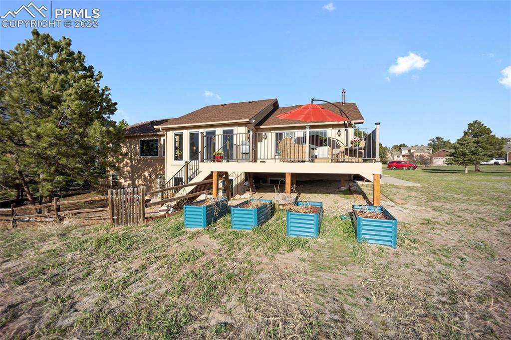 Rear view of house with fence, stairway, a deck, and a yard