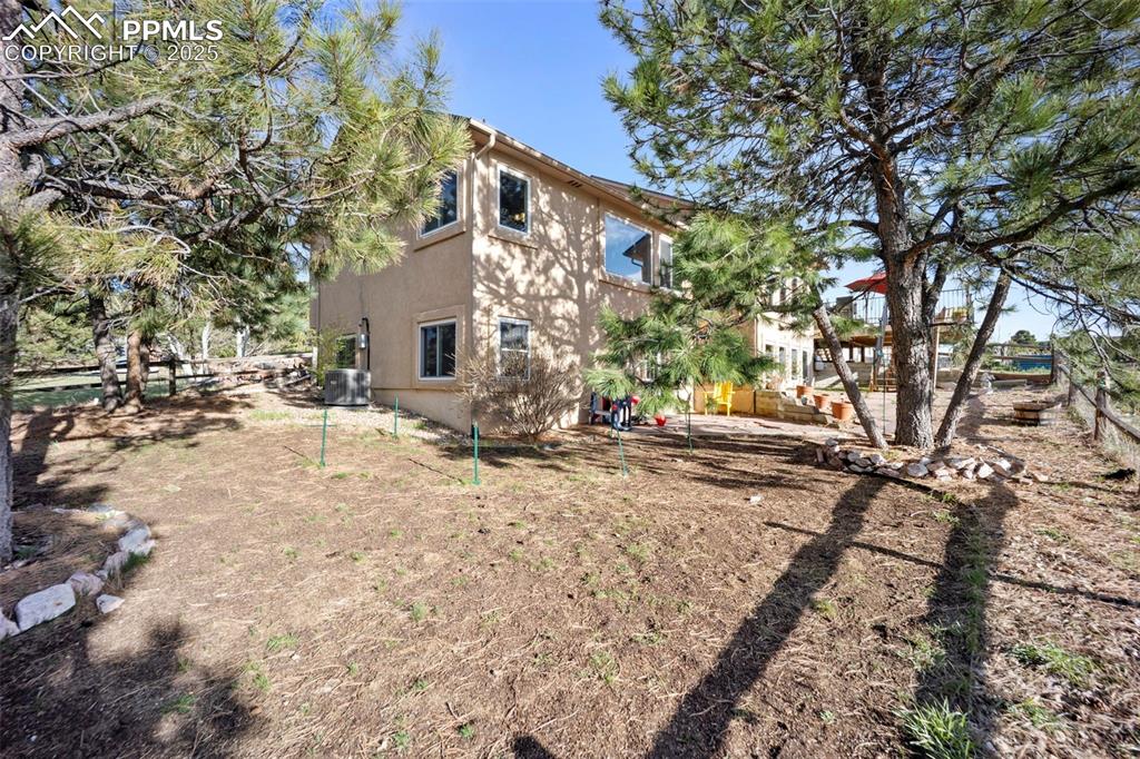 View of side of home featuring fence, stucco siding, and cooling unit