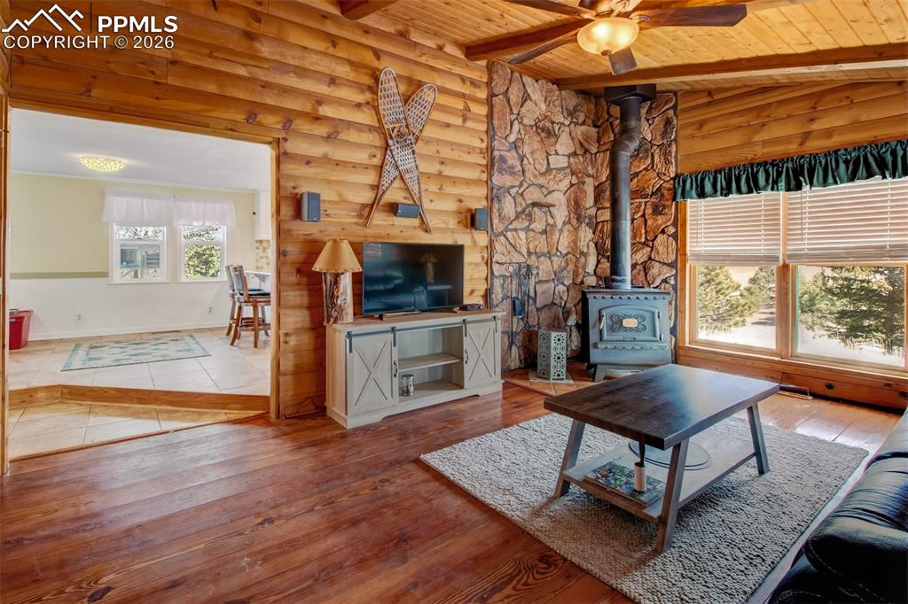 Living room with wood burning stove, wood accents all around along with wood flooring.
