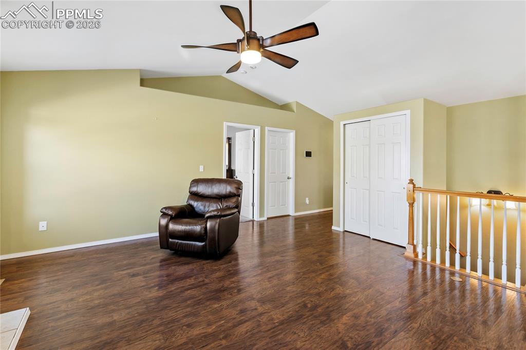 Sitting room with dark wood-style flooring, an upstairs landing, and a ceiling fan