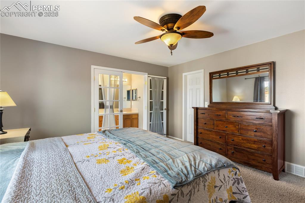 Carpeted bedroom with a ceiling fan and ensuite bathroom
