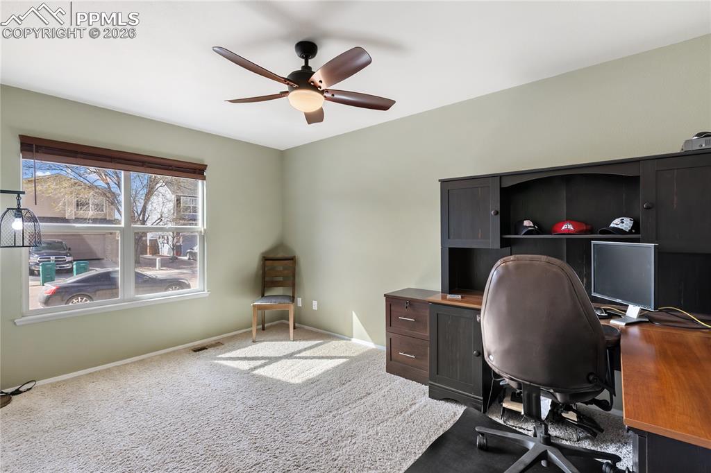 Carpeted office with ceiling fan and baseboards