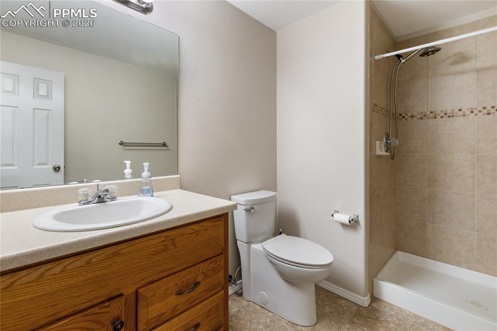 Full bath with vanity, a stall shower, light tile patterned flooring, and a textured wall