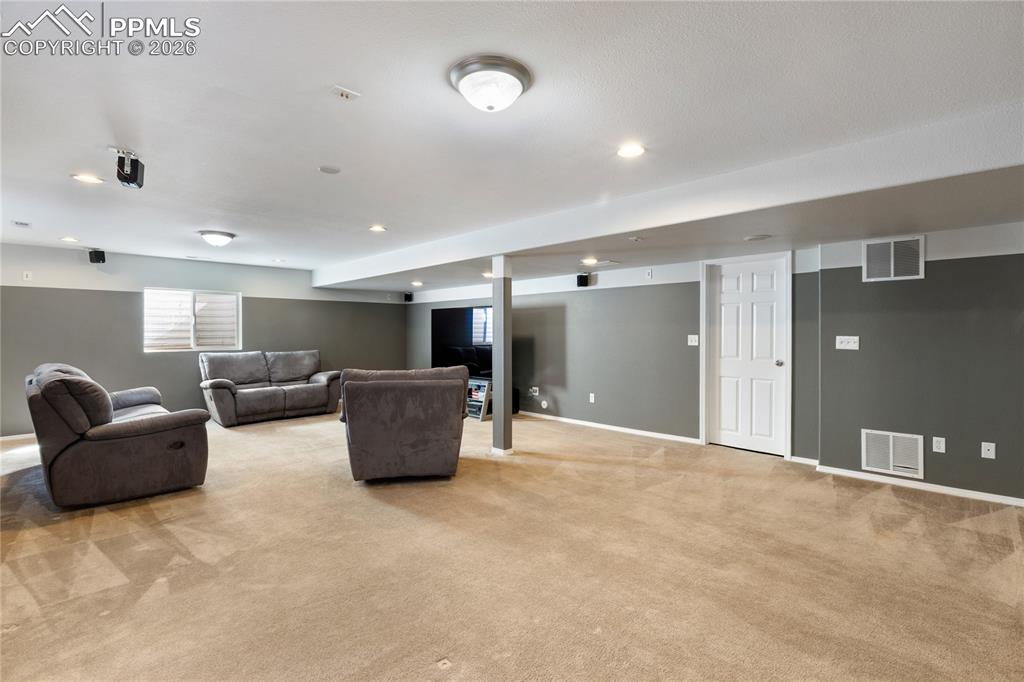 Living area with light carpet and recessed lighting