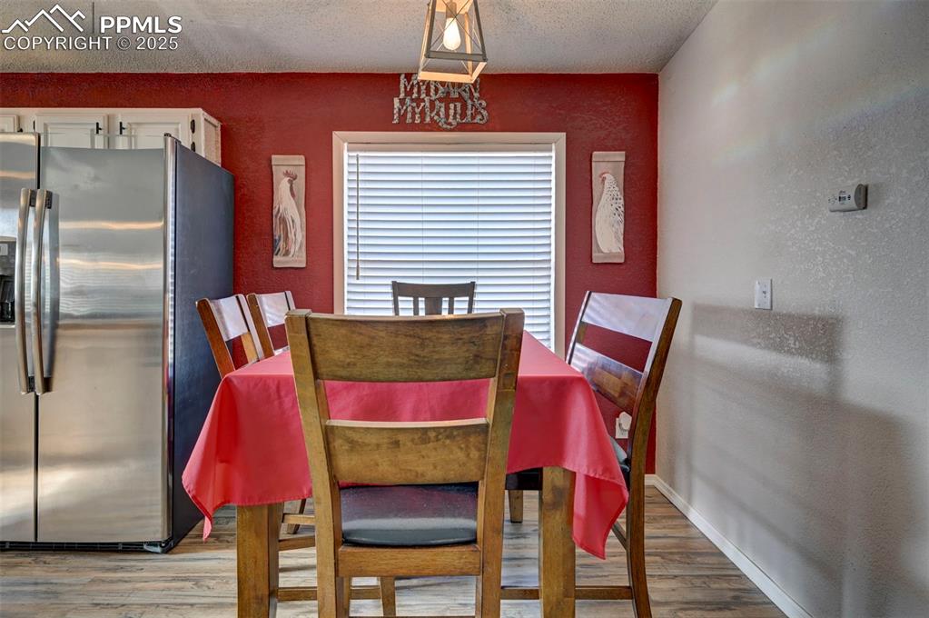 Dining space with light wood-type flooring, a textured wall, and a textured ceiling