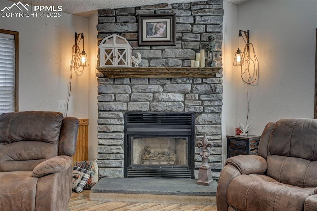 Living room featuring wood finished floors, a textured ceiling, a fireplace, and a textured wall
