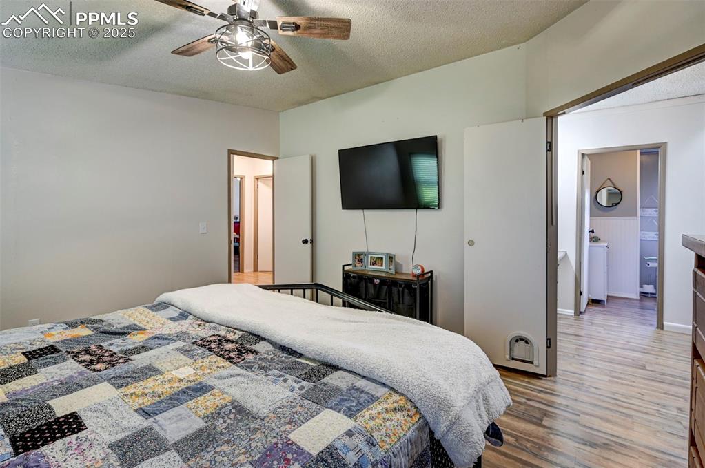 Bedroom with a textured ceiling, light wood finished floors, and ceiling fan