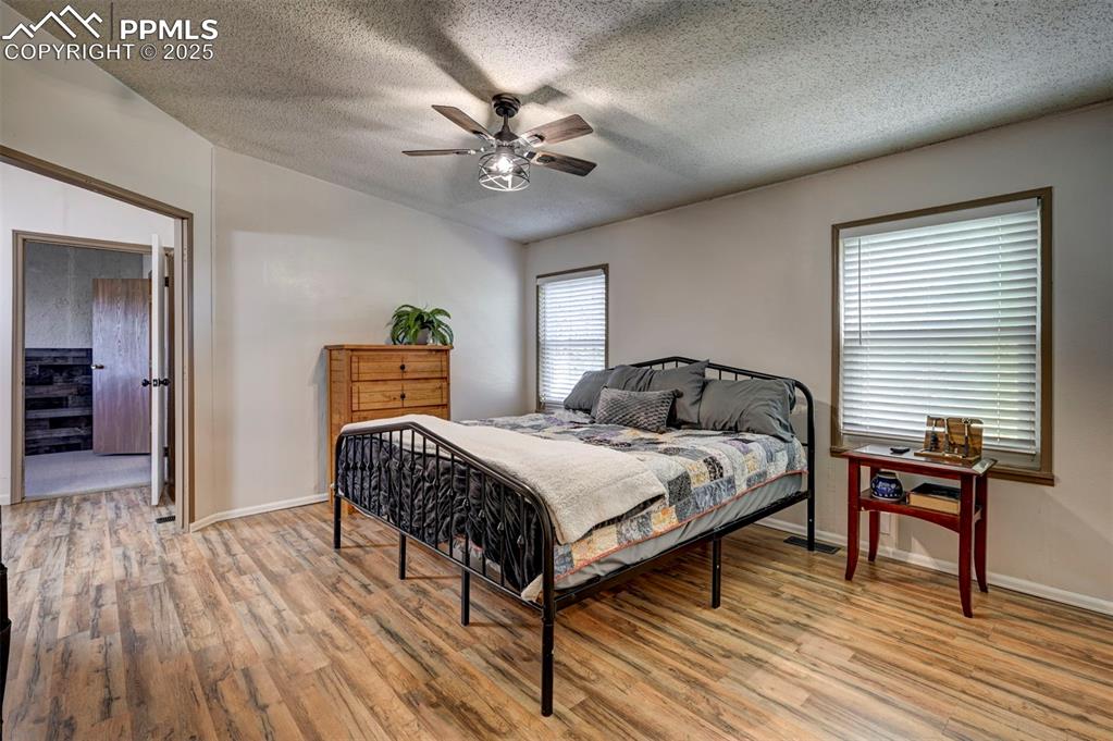 Bedroom with light wood-style flooring, a textured ceiling, and ceiling fan