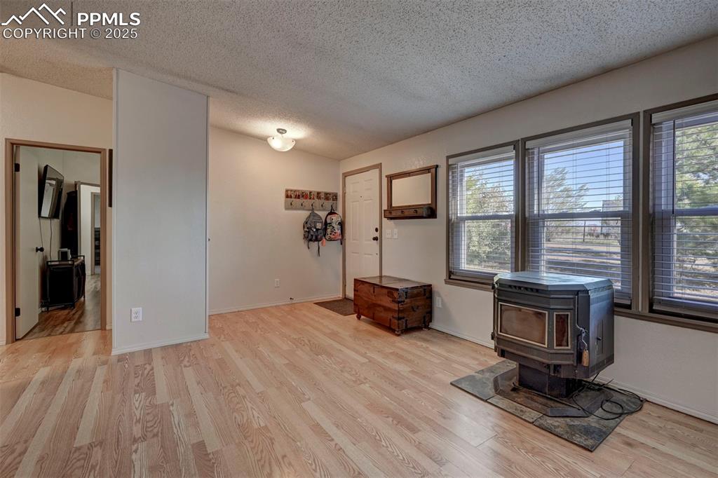 Entrance foyer with a wood stove, a textured ceiling, and light wood-style flooring