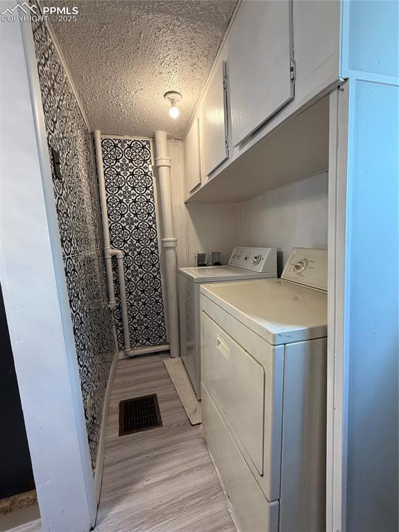 Washroom featuring separate washer and dryer, and cabinet space
