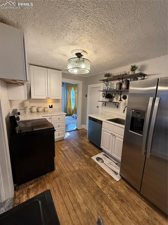 Kitchen featuring refrigerator, range, and white cabinetry, 