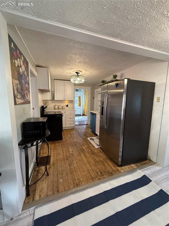Kitchen with fridge, hardwood / wood-style flooring, dishwasher, light countertops, and white cabinetry