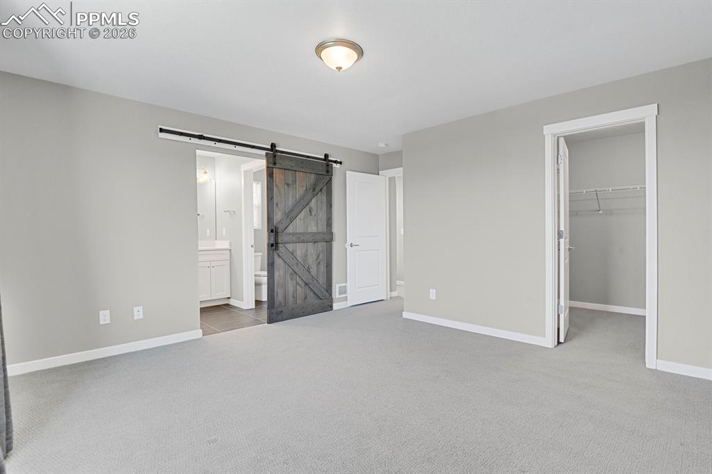 Primary bedroom and barn door leading into en suite bathroom