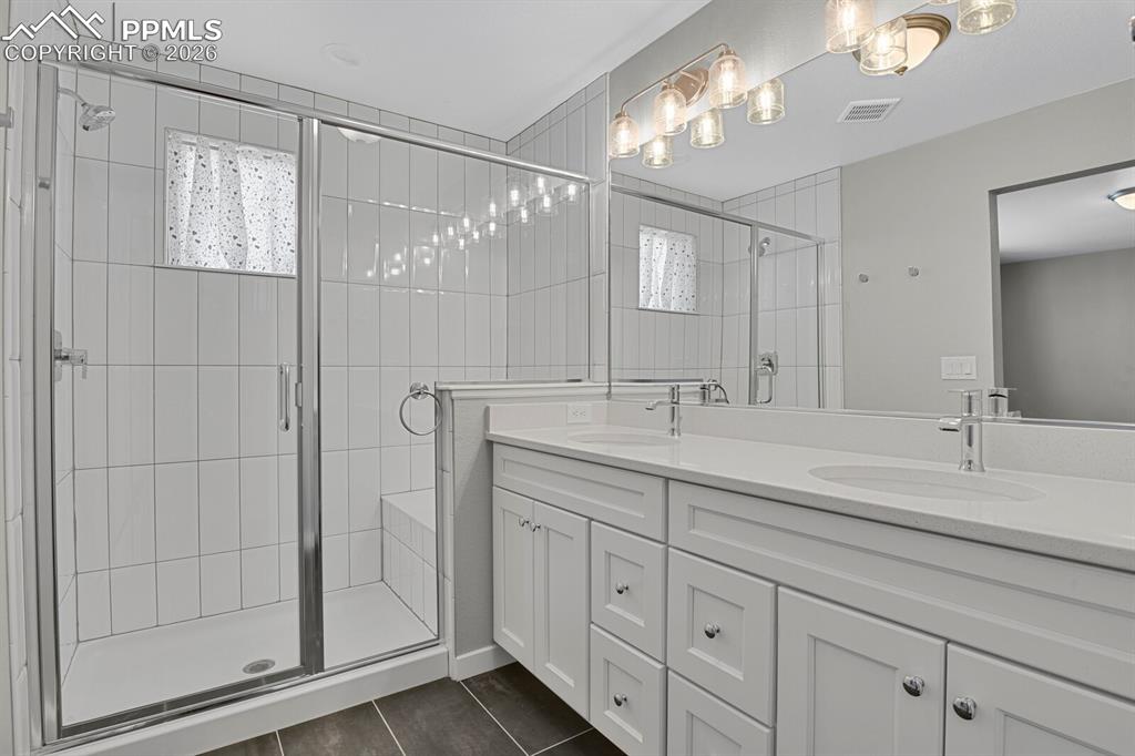Primary Full bath featuring double vanity, a stall shower with plenty of natural light