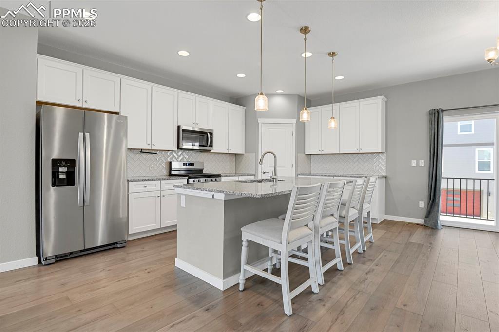 Kitchen with appliances with stainless steel finishes, a breakfast bar, white cabinetry