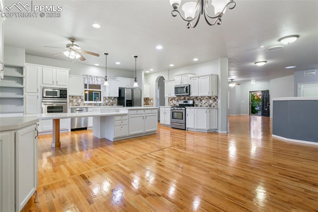 Kitchen featuring stainless steel appliances, ceiling fan, backsplash, light countertops, and recessed lighting