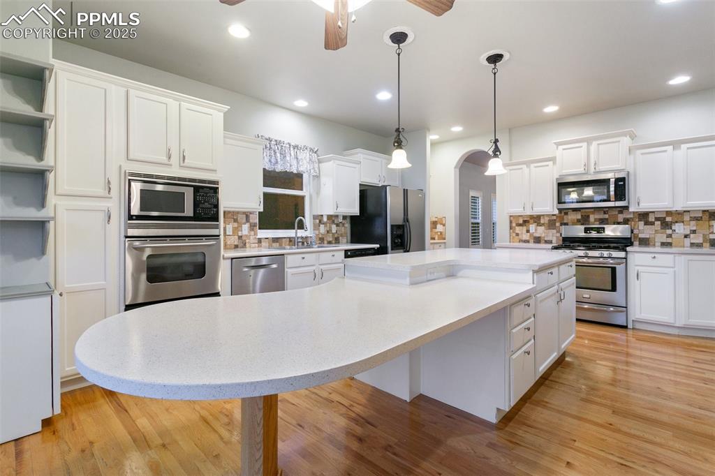Kitchen featuring appliances with stainless steel finishes, a kitchen island, a ceiling fan, white cabinetry, and recessed lighting