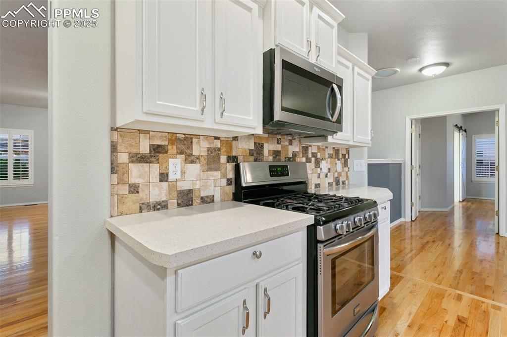 Kitchen with appliances with stainless steel finishes, tasteful backsplash, light wood-style floors, and light countertops