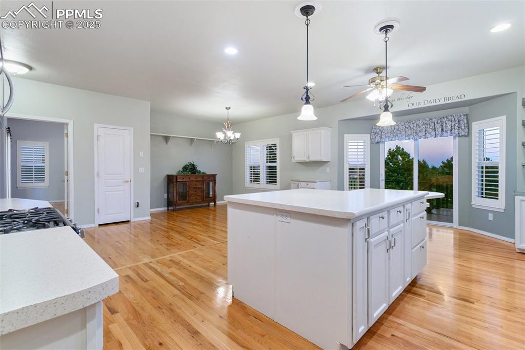 Kitchen with a kitchen island, white cabinetry, light wood-style floors, light countertops, and a chandelier