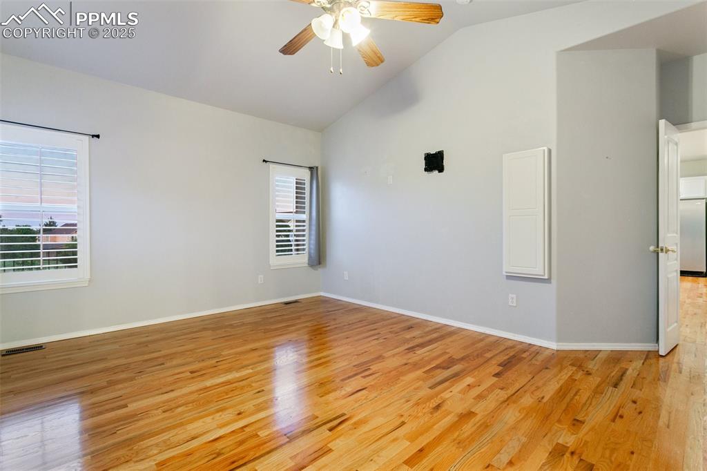 Spare room with light wood finished floors, a ceiling fan, and high vaulted ceiling