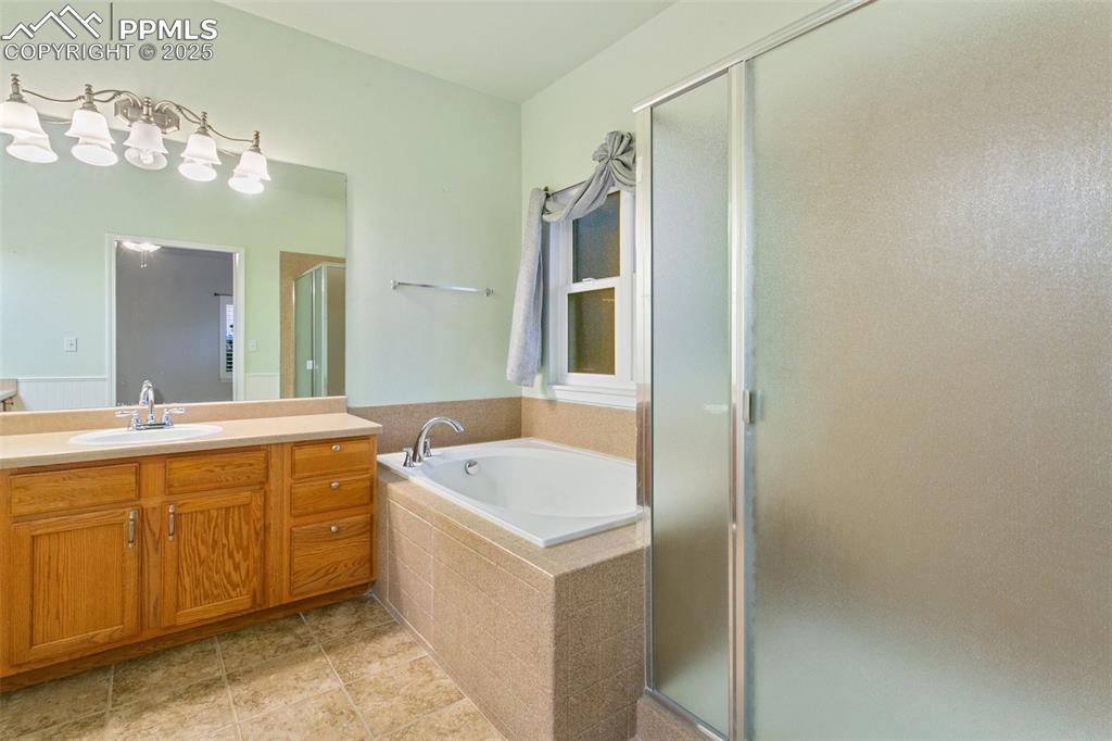 Full bath with vanity, a stall shower, a bath, and tile patterned floors