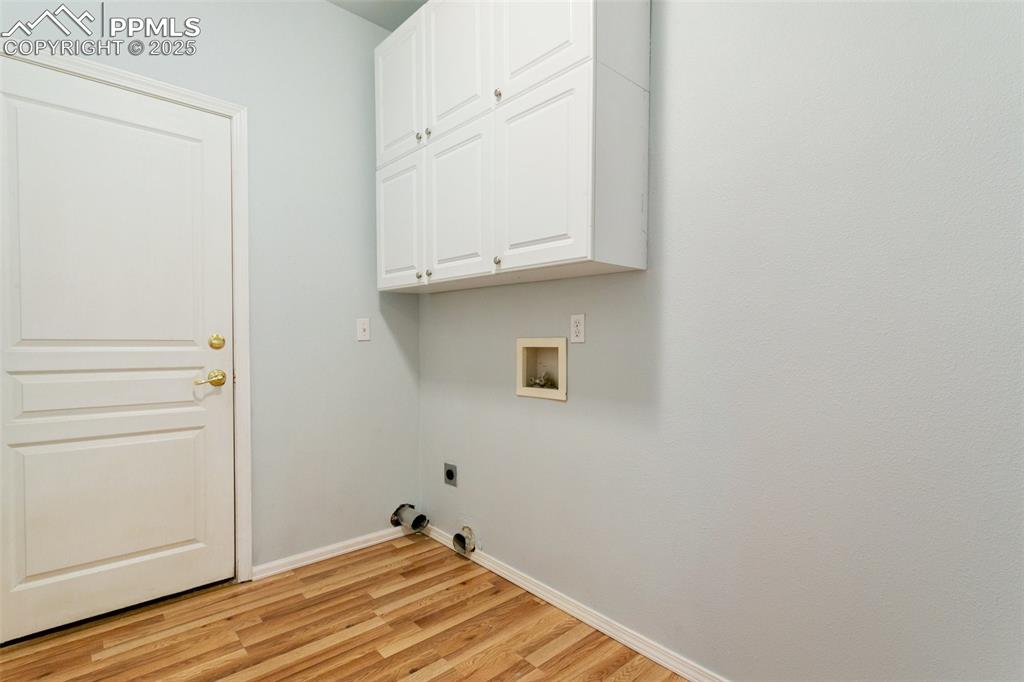 Laundry room with hookup for an electric dryer, cabinet space, hookup for a washing machine, light wood-style flooring, and hookup for a gas dryer