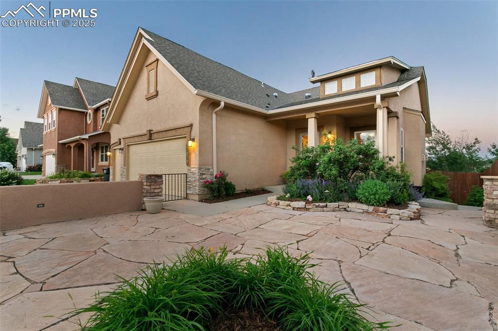 View of front of property with stucco siding, concrete driveway, a garage, and a shingled roof