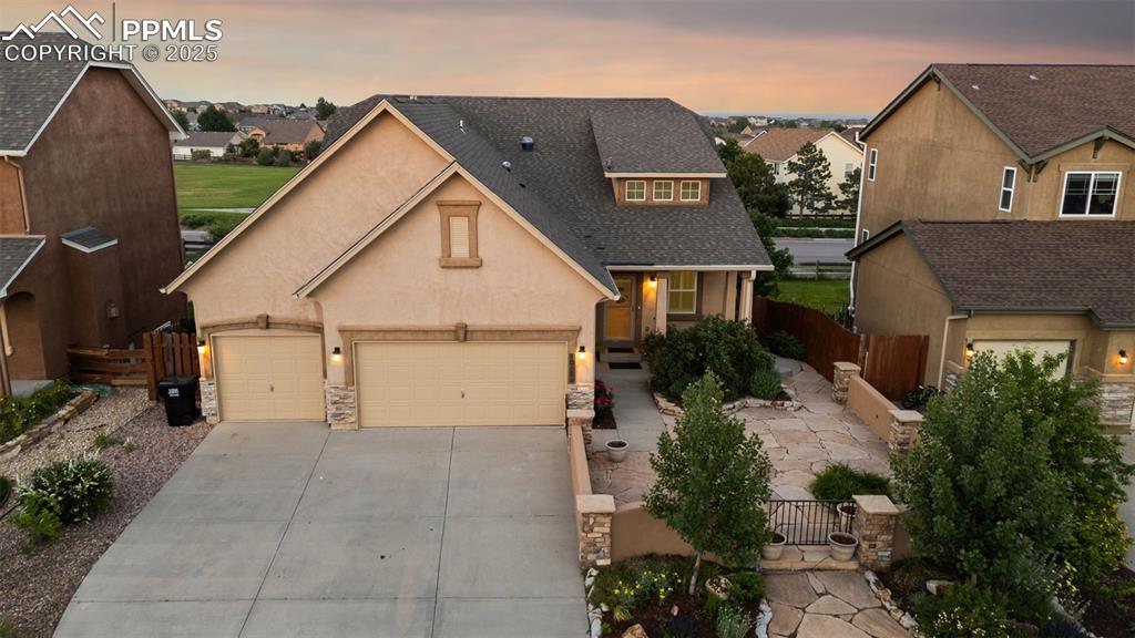 Traditional home with concrete driveway, stucco siding, a residential view, an attached garage, and a shingled roof