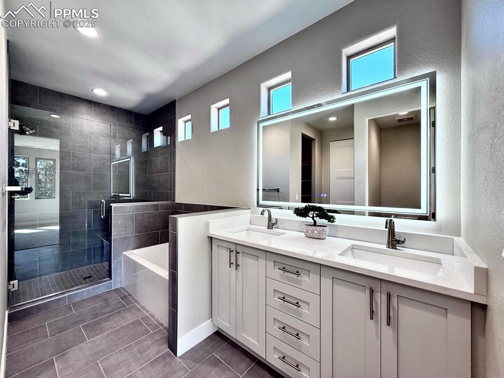 Luxurious Primary Bathroom with Double Vanities, Quartz Countertops, Heated Mirror to avoid fogging, Deep Soaking Tub, Large Shower with Bench and Glass Door.