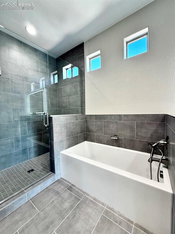 Luxurious Primary Bathroom with Double Vanities, Quartz Countertops, Heated Mirror to avoid fogging, Deep Soaking Tub, Large Shower with Bench and Glass Door.