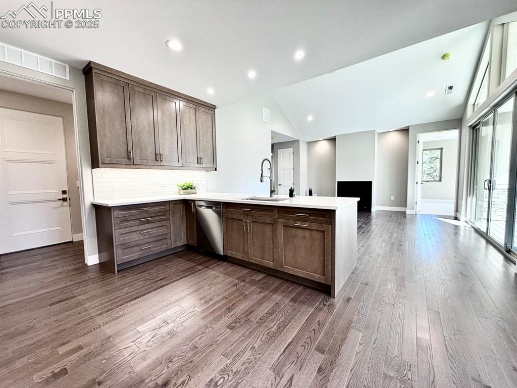 Full Sized Gourmet Kitchen with Quartz Countertops, Cabinets to the Ceiling, and Induction Range, Included Stainless Steel Fridge, and Wood Flooring.