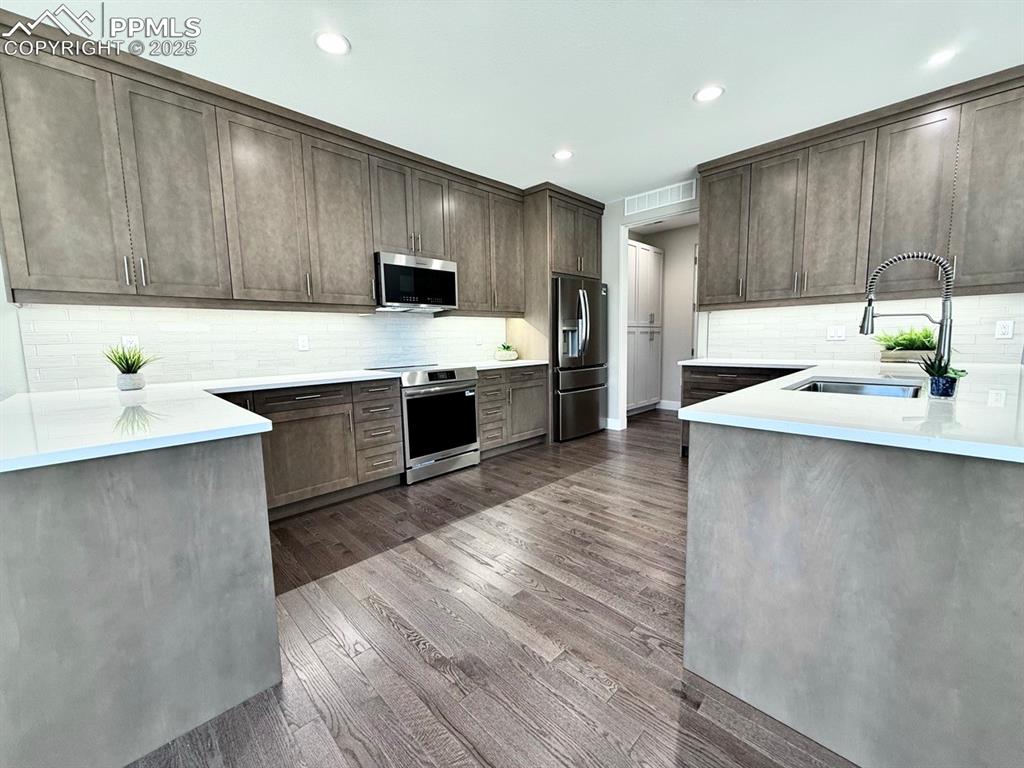 Full Sized Gourmet Kitchen with Quartz Countertops, Cabinets to the Ceiling, and Induction Range, Included Stainless Steel Fridge, and Wood Flooring.