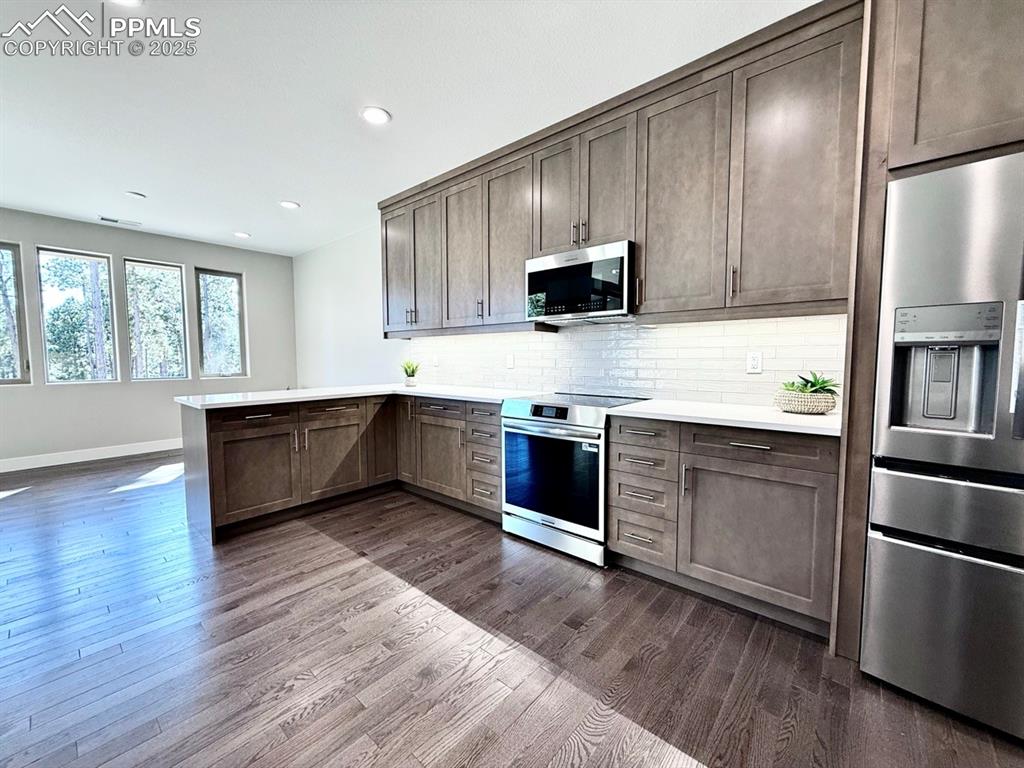 Full Sized Gourmet Kitchen with Quartz Countertops, Cabinets to the Ceiling, and Induction Range, Included Stainless Steel Fridge, and Wood Flooring.