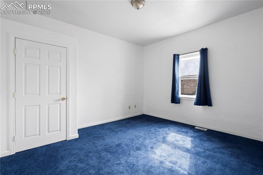 Unfurnished room with baseboards and dark colored carpet