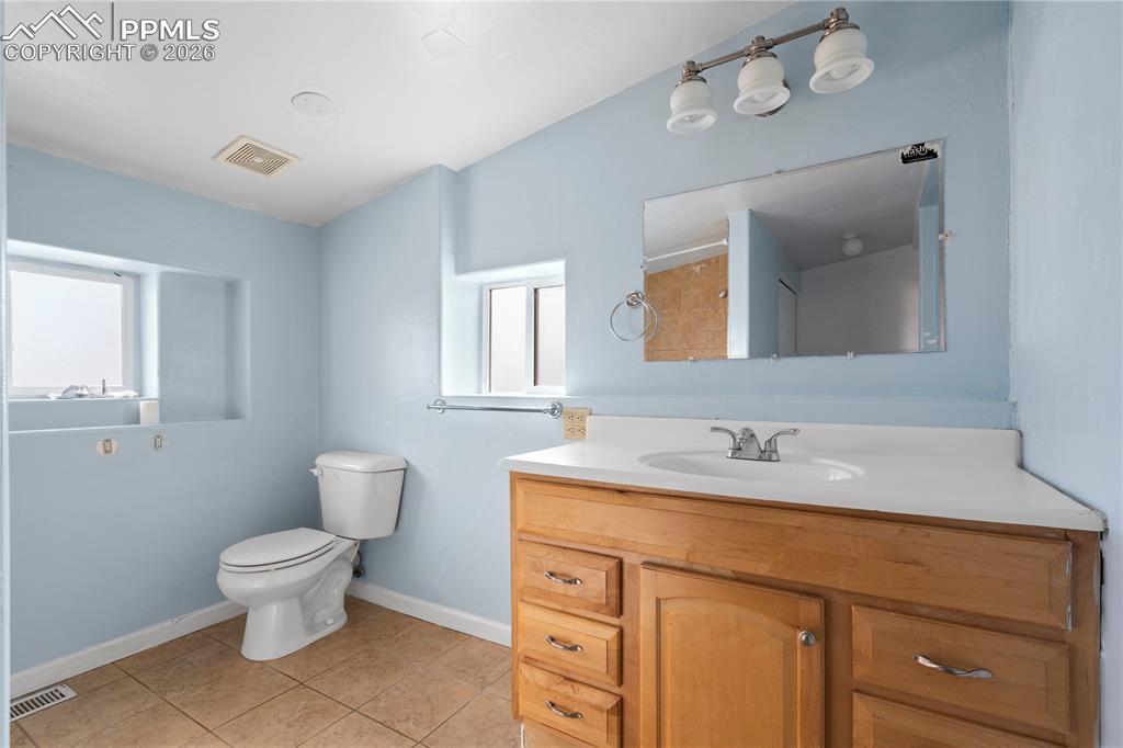 Bathroom with vanity, light tile patterned floors, and a shower
