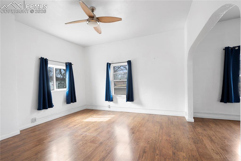 Spare room featuring wood finished floors, ceiling fan, and arched walkways