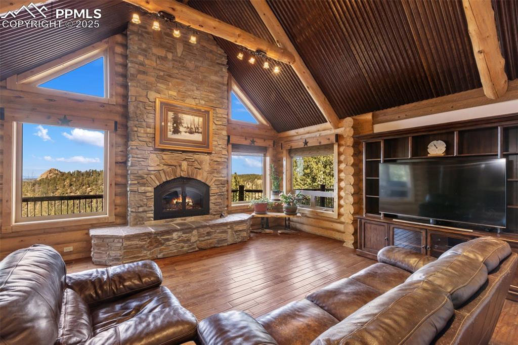 Living room featuring hardwood / wood-style flooring, beamed ceiling, high vaulted ceiling, and a fireplace