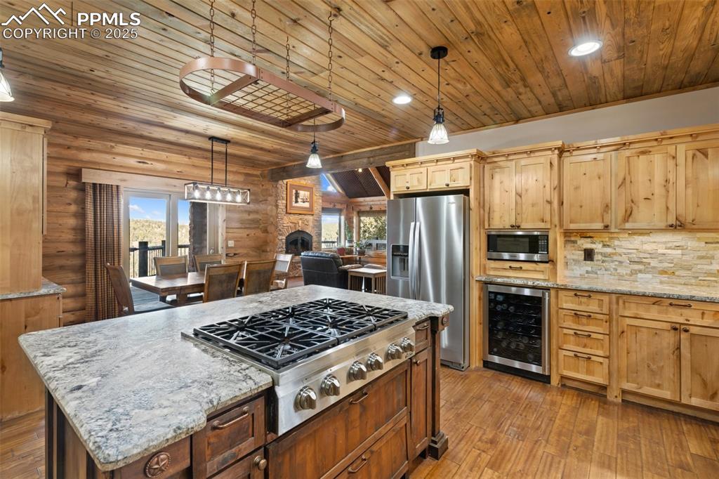 Kitchen featuring light stone counters, stainless steel appliances, pendant lighting, wooden ceiling, and recessed lighting