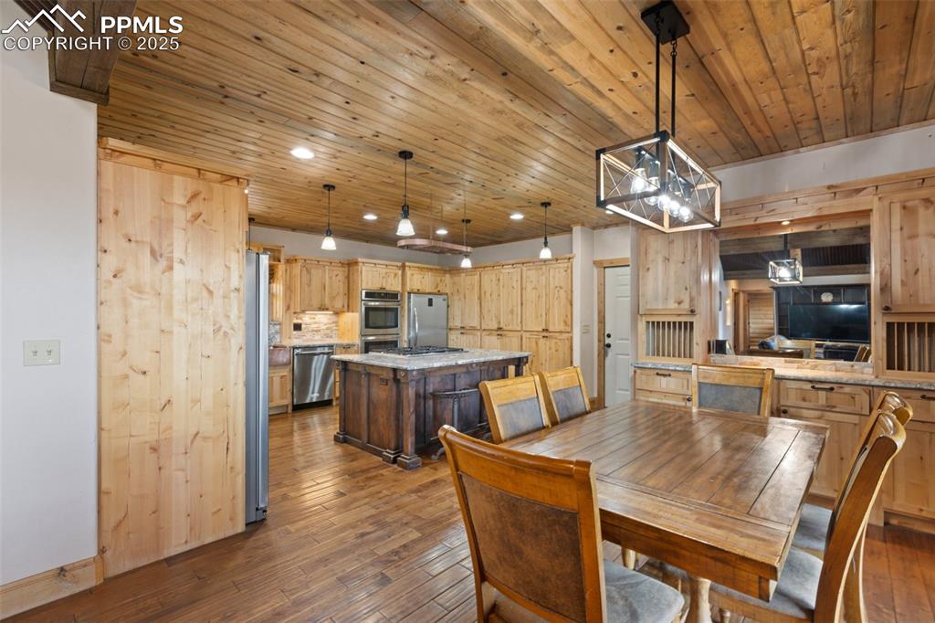 Dining area featuring dark wood-type flooring, a chandelier, recessed lighting, and wooden ceiling